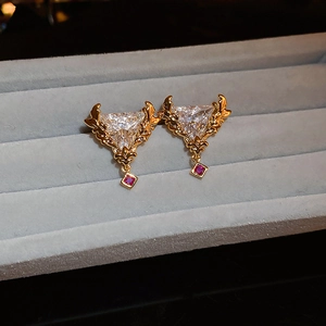 Vue macro de boucles d'oreilles triangulaires vintage dorées sur écrin en velours