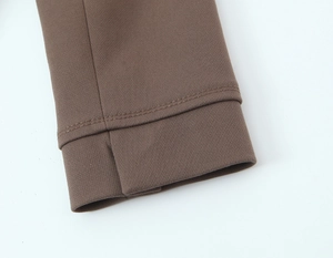 Détail de manchette marron foncé montrant des doubles surpiqûres et un tissu en sergé