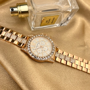 Detail of luxury gold quartz watch with pavé zircon bezel on elegant silk fabric