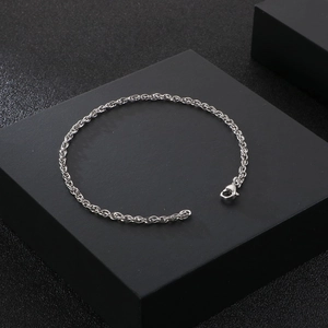 Polished stainless steel curb chain bracelet with lobster clasp on a black platform