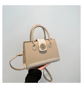 Détail du sac beige avec empiècements texture croco et boucle fleur dorée