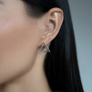 Close-up of geometric triangle silver earring worn by model for elegant style