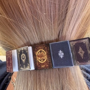 Close-up of vintage miniature book hair clips with gold patterns on blonde hair