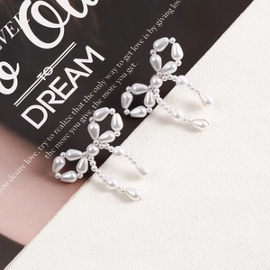 Close-up of vintage bow earrings with white pearls on a stylish magazine backdrop