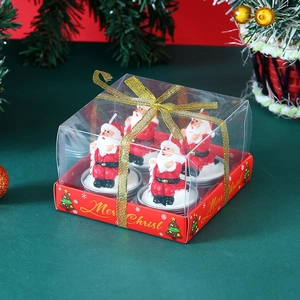 Close-up of 4 Santa Claus Christmas candles in gift box with festive golden ribbon