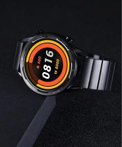 Detailed view of the smart watch with black stainless steel band on a textured surface