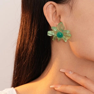 Detail of light green translucent resin flower stud earring worn by a model in sunlight