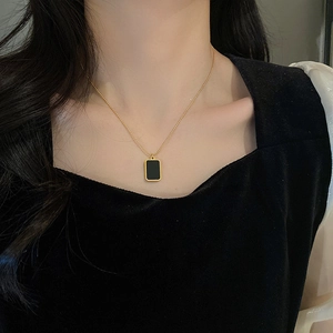 Dettaglio della collana dorata con orso e pendente nero sulla scollatura della modella