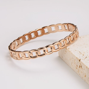 Polished rose gold stainless steel hollow chain bracelet on a textured stone base