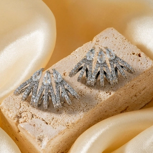 Elegant silver starburst earrings with sparkling white zircon stones on silk background
