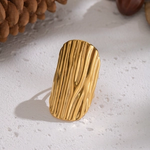 Detailed view of gold wide-band ring with wavy texture on natural stone surface