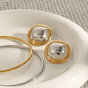 Detail view of two-tone square earrings in polished gold and silver stainless steel