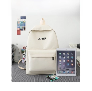 Detail view of off-white canvas backpack with ATWF logo and blue astronaut pendant