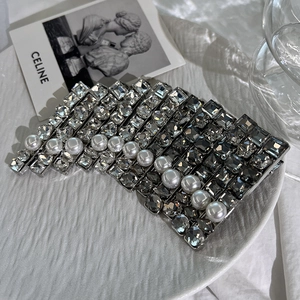 Detailed close-up of a silver hair clip featuring black crystals and white pearls