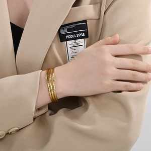 Close-up of three-piece gold-tone layered bracelets with hammered metal texture