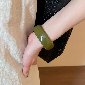 Détail d'un bracelet jonc large en acrylique vert olive poli avec une finition lisse