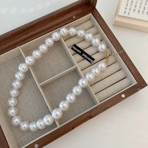 Detail of white large pearl necklace with golden lobster clasp on velvet jewelry box