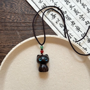 Vue détaillée du pendentif chat en bois noir sculpté main avec des yeux en cristal