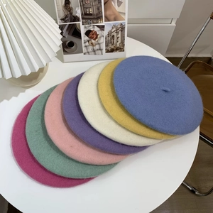 Flat lay of colorful wool beret hats in blue, yellow, and pink on a white table