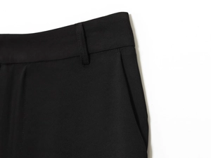 Detailed view of black trousers waist featuring belt loops and side pocket stitching