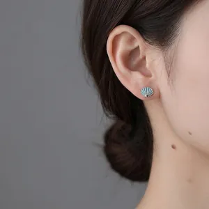 S925 sterling silver shell stud earrings with blue enamel finish shown on ear