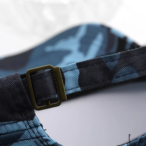 Macro detail of military cap showing camouflage fabric and bronze metal adjustment buckle