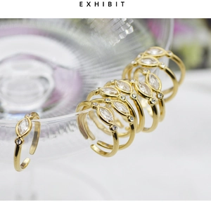 Detail of gold adjustable rings with marquise cut zircon on a glass edge