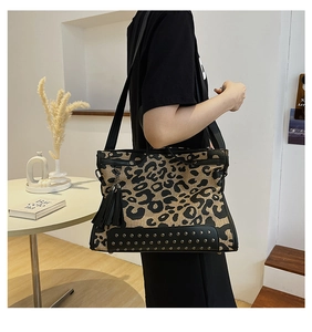 Detail of leopard print tote bag with black tassel charm and protective bottom studs