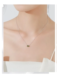 Gros plan d'un collier en argent sterling avec pierre verte ovale portée sur la clavicule