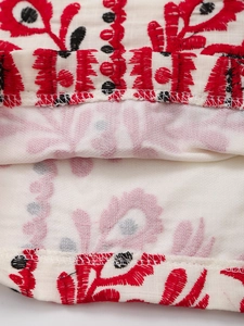 Détail macro de broderie rouge et noire sur short en lin de coton beige de qualité