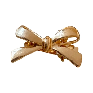 Polished gold alloy mini bow hair clip with a minimalist 3D design on white background
