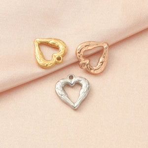 Three textured heart pendants in gold, rose gold, and silver on pink silk for DIY jewelry