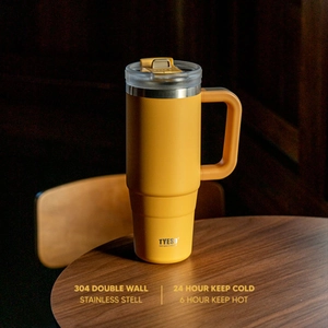 Yellow TYESO 40oz insulated stainless steel mug with handle and straw on a wood table