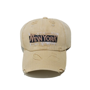 Close-up of New York embroidery on distressed cotton canvas baseball cap with ripped details