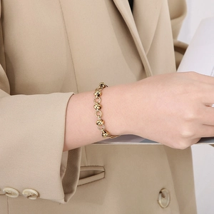 Detailed view of a gold beaded chain bracelet worn on a wrist in soft natural light