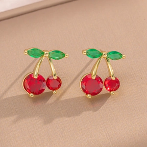 Elegant gold cherry stud earrings with red and green gemstones on beige fabric