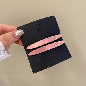 Close-up of two pink long acrylic hair clips with golden Barrette LaFrance text