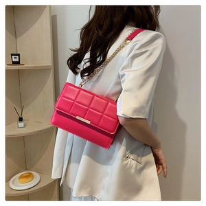 Macro detail of quilted magenta shoulder bag with gold chain and metal clasp