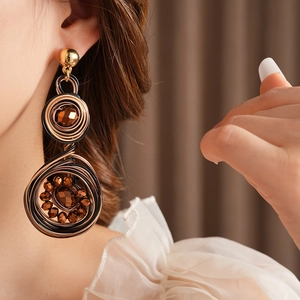 Close-up of vintage bronze woven hoop earrings with brown beads on a female model