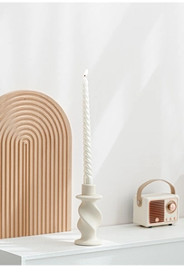 Primo piano di una candela a spirale bianca su un portacandele in ceramica beige a torsione