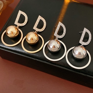Detail of silver needle earrings with zircon letter D, gold and silver ball pendants