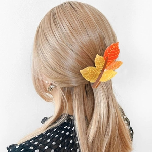 Detail of translucent maple leaf hair claw clip in orange and red on blonde hair