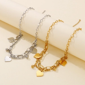 Detail of double-layer chain bracelets in gold and silver with heart-shaped pendants
