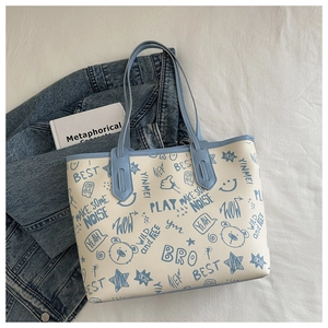 Detail of large beige tote bag with blue graffiti prints and dual shoulder straps