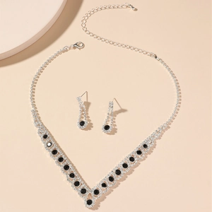 Detail of silver V-shaped necklace and drop earrings with black gemstones and rhinestones