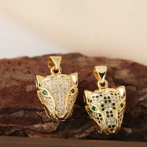 Cute gold leopard pendants with cubic zirconia and green gem eyes on tree bark background