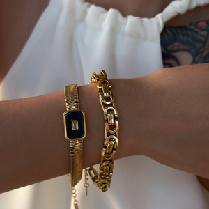 Close-up of gold-plated snake chain bracelet with black rectangular enamel detail