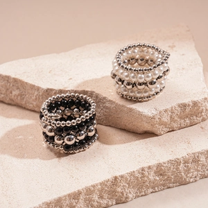Detail of layered elastic beaded rings with faux pearls and silver metal beads