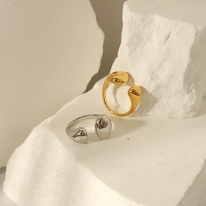 Polished gold and silver stainless steel open rings displayed on a white textured stone surface