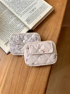 Quilted floral cotton pouches with snap closures displayed on a rustic wooden table surface